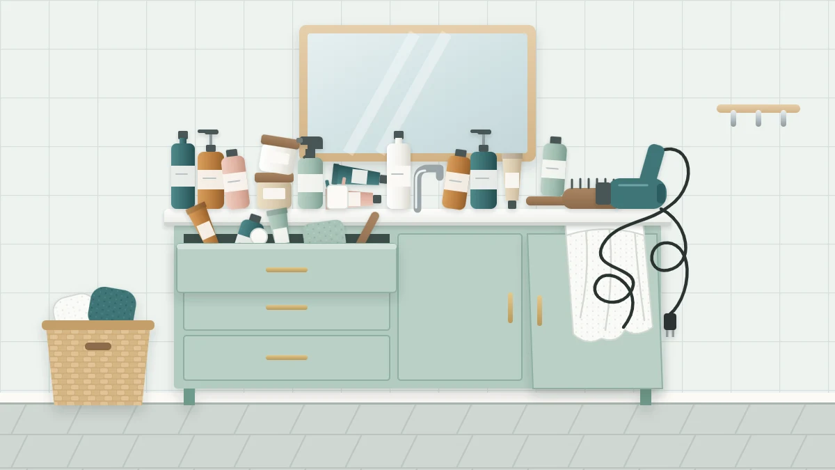 A cluttered vanity with a counter crowded by bottles, tubes, a hairbrush and a tangled cord, an overflowing drawer and a slumped towel