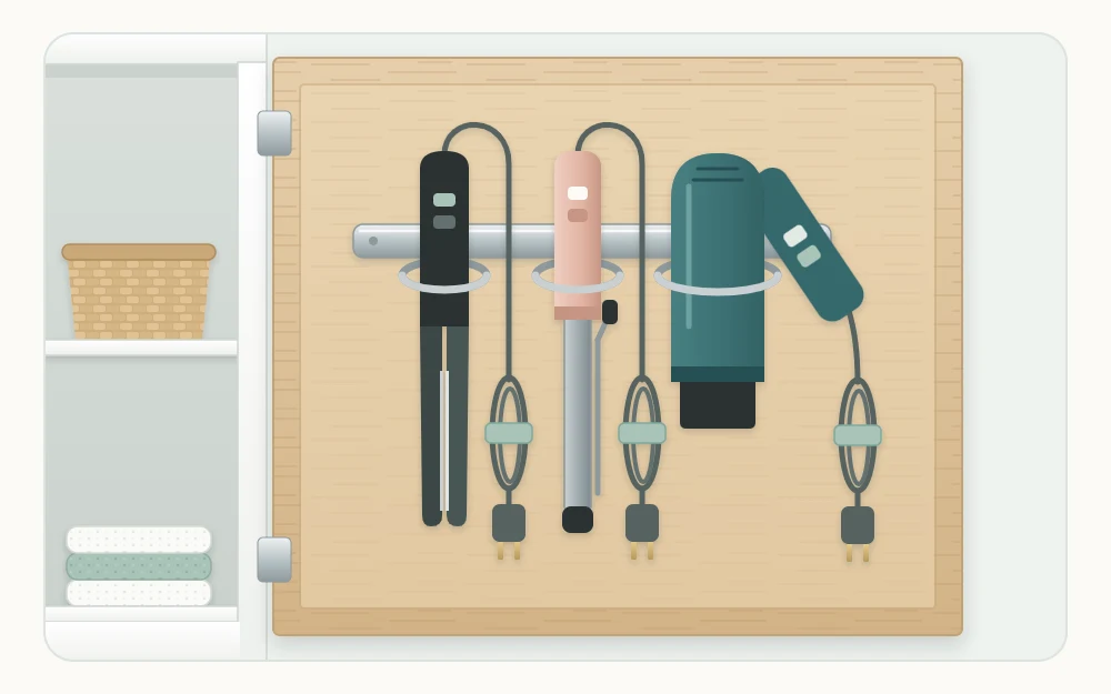 Inside of an open cabinet door with a three-ring holder carrying a hair dryer and two styling irons, cords in loose tied loops