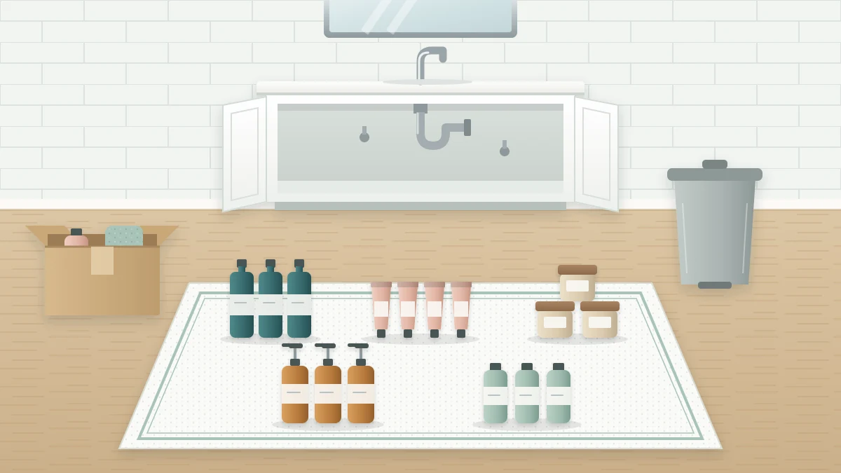 A towel spread on a bathroom floor with bottles, tubes and jars sorted into five groups in front of an empty open vanity cabinet
