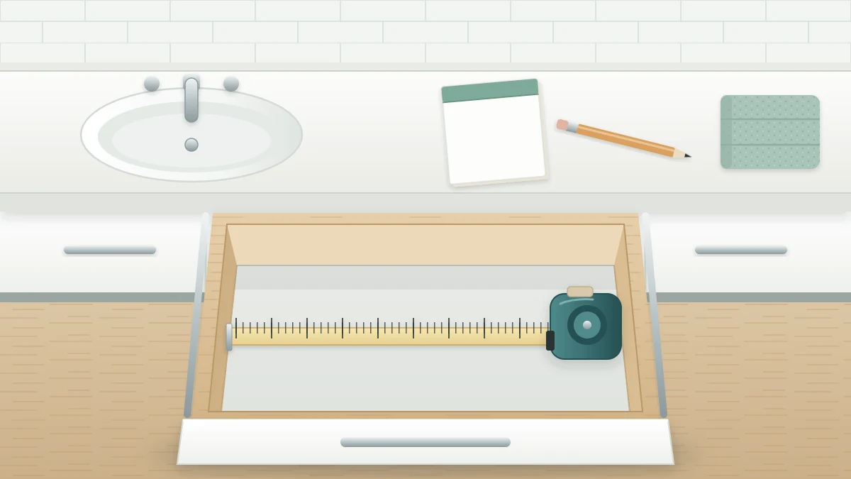 An empty open vanity drawer with a retractable tape measure stretched across its inside width, and a pencil and blank notepad on the counter